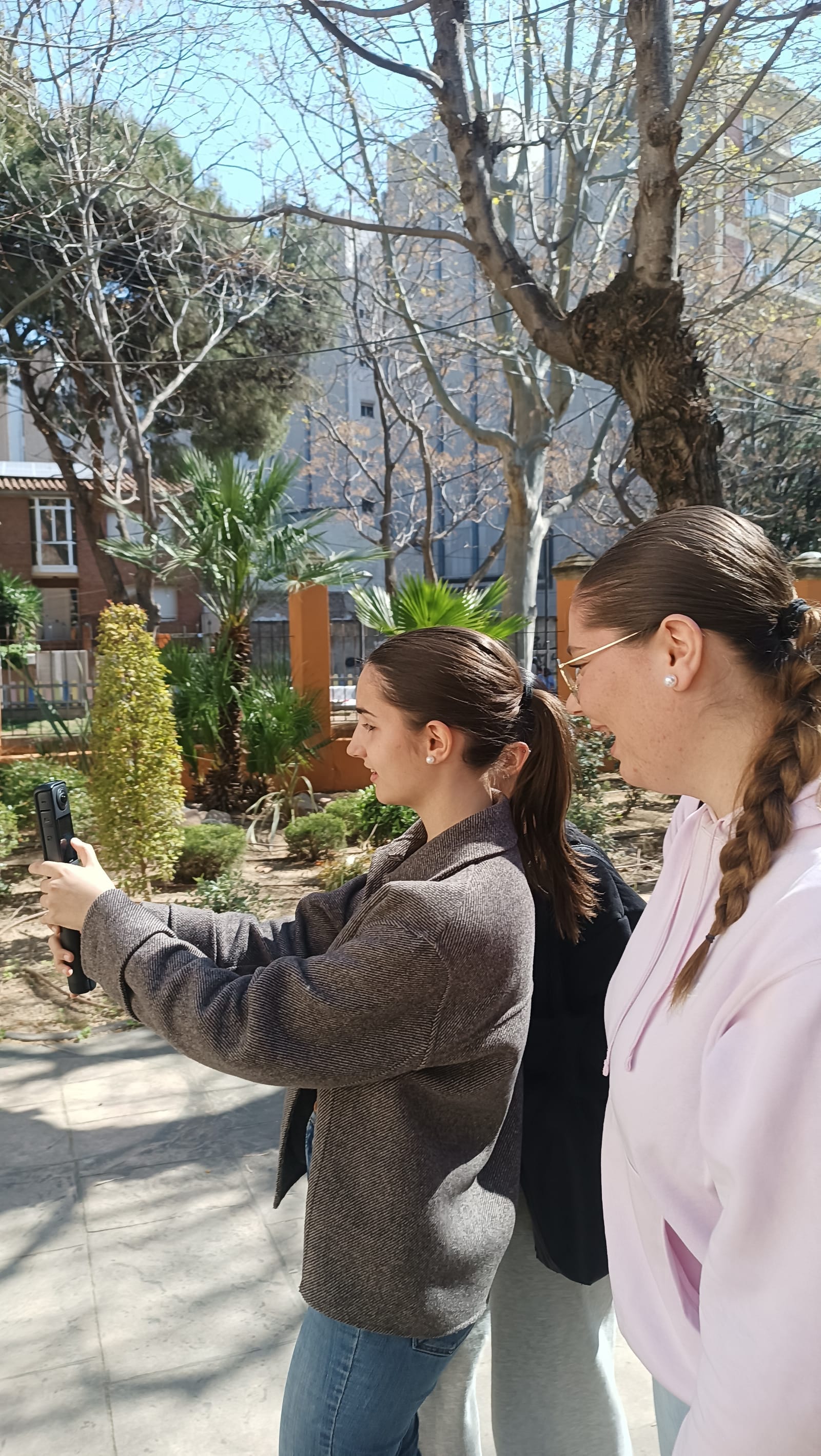 Dues estudiants graven el jardí amb la càmera 360
